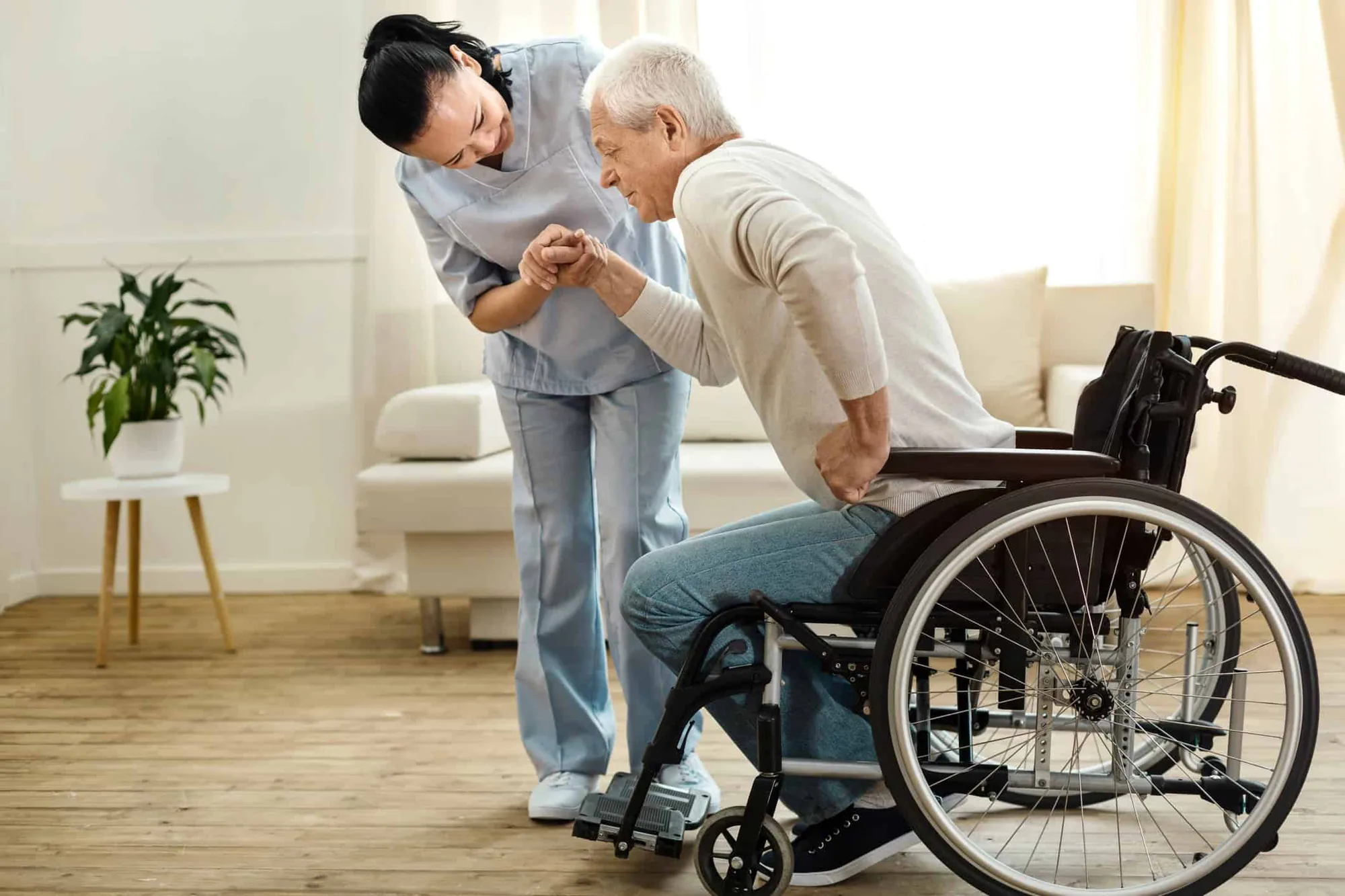 Caregiver assisting a resident from a wheelchair with steady hands
